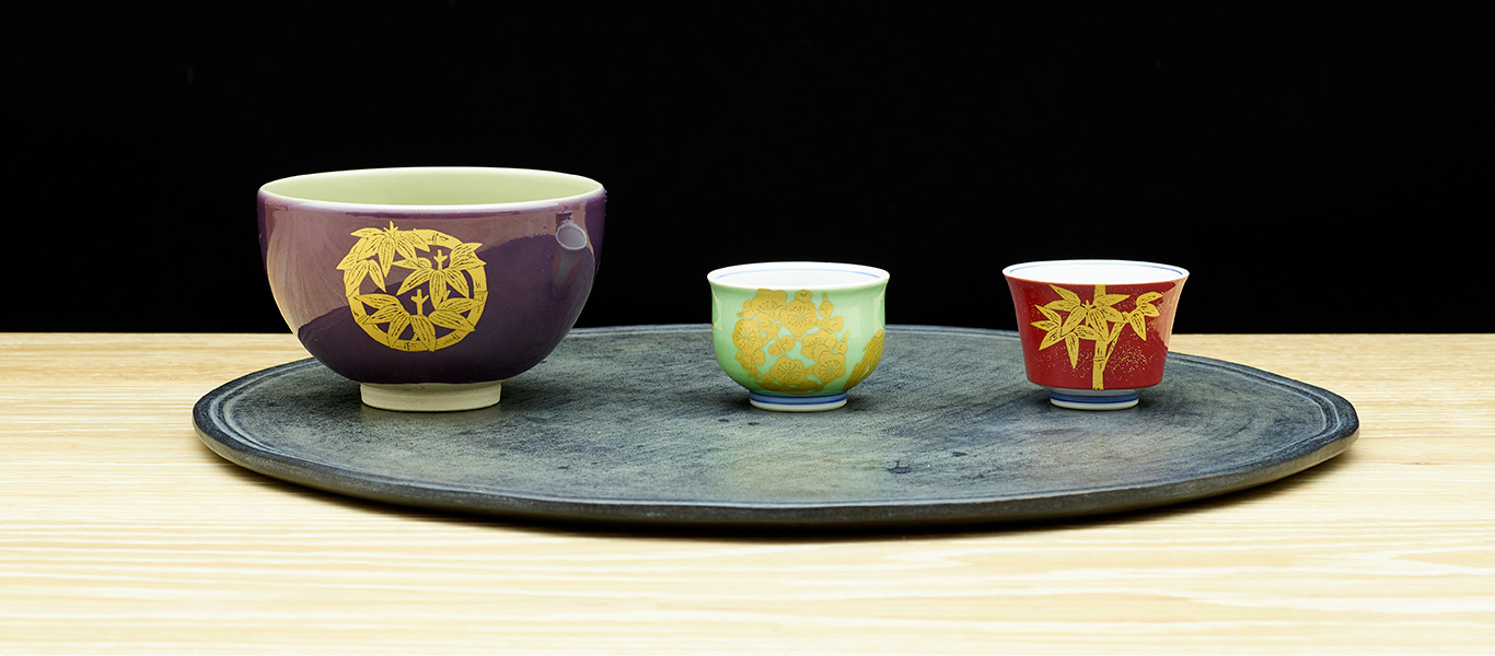 写真左より、𠮷田美統作「釉裏金彩 四君子丸紋 茶盌」、「釉裏金彩 四君子丸紋 ぐい吞」、「釉裏金彩 竹文 ぐい吞」