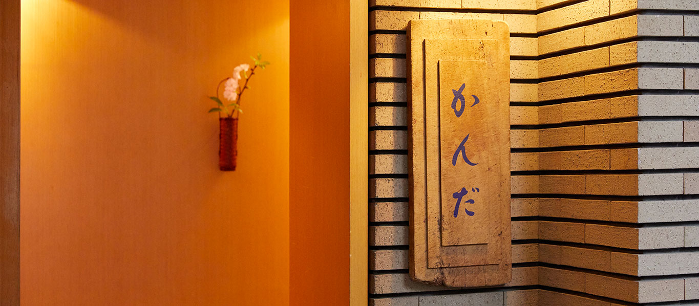 店の看板は実家のまな板を利用したもの。徳島で鮮魚店、仕出しの店を営んでいた父親の店を継いだつもりで、徳島の名産、愛染で文字を染めた。