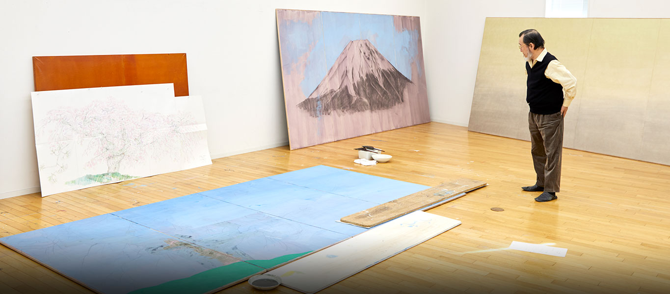 アトリエで。日本画の場合、一般的に画面を床に寝かせて制作する。途中で画面を起こして全体で確認したら、また寝かせる。大作ではその作業に手間がかかる。