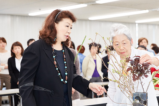 師範の有資格者を対象としたクラスでの指導風景。初心者の場合、自分が好きな材料や花器を選ぶことも学びとなるが、キャリアが長くなるほど幅を広げることも大切に。そこで、この日の参加者にはくじ引きで当たった花器と材料でいけてもらい、「いつもの自分」から逸脱することを促した。