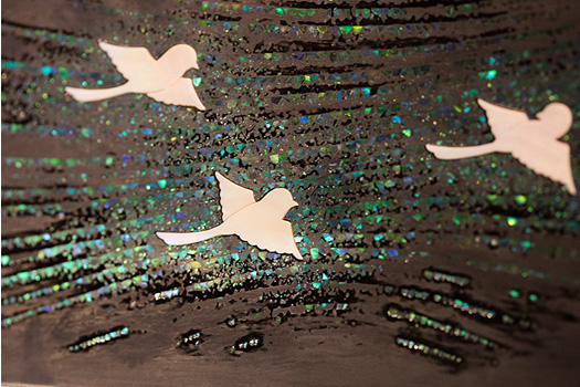 蒔絵螺鈿飾箱「春映」制作工程④ 側面の螺鈿　側面は、微細な青い貝を並べ置き、春の空気を表現。中心の白い鳥は、花を楽しむ人の暗喩。鳥の形に彫り込んだ部分に、厚さ1mmの厚貝がぴたりとおさまる。
