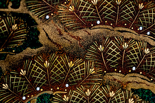 側面の青松は、一部に緑漆を用い松葉を表現。幹は、古代の蒔絵に使われていた、金を鑢でおろしただけの粉で老木の肌を表した。点々と置かれた真珠が松葉に雨露のように光る。
