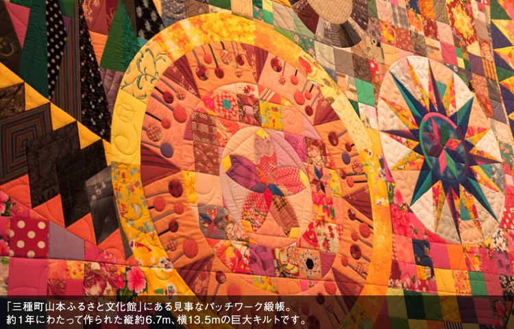 「三種町山本ふるさと文化館」にある見事なパッチワーク緞帳。約1年にわたって作られた縦約6.7m、横13.5mの巨大キルトです。
