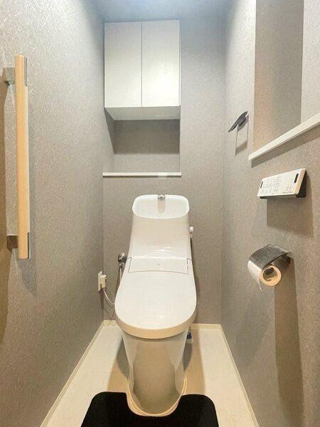 落ち着いた色調のトイレです。1年中快適に使用できる、温水洗浄便座付き。吊戸棚が備わっています。