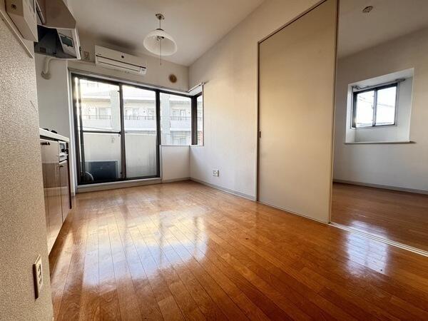 北東から南東にかけて窓が配された、明るいLDK。エアコンが設置されており、初期費用が抑えられます。