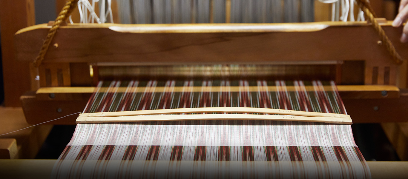 1,320本の糸がかけられている機。模様が浮かんでいるのは、5段階に分けて染めた絣（かすり）糸を使っているため。紬で取り組んできた絣の技術を、紋紗に応用した。