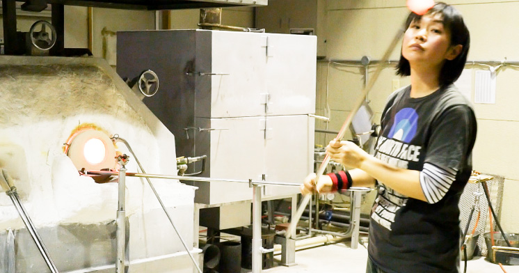 高温のガラスが巻き取られた吹き竿を手慣れた様子で扱うベテランの倉島さん。グラスだと約15分ででき、1日20個から30個ほどつくるという。